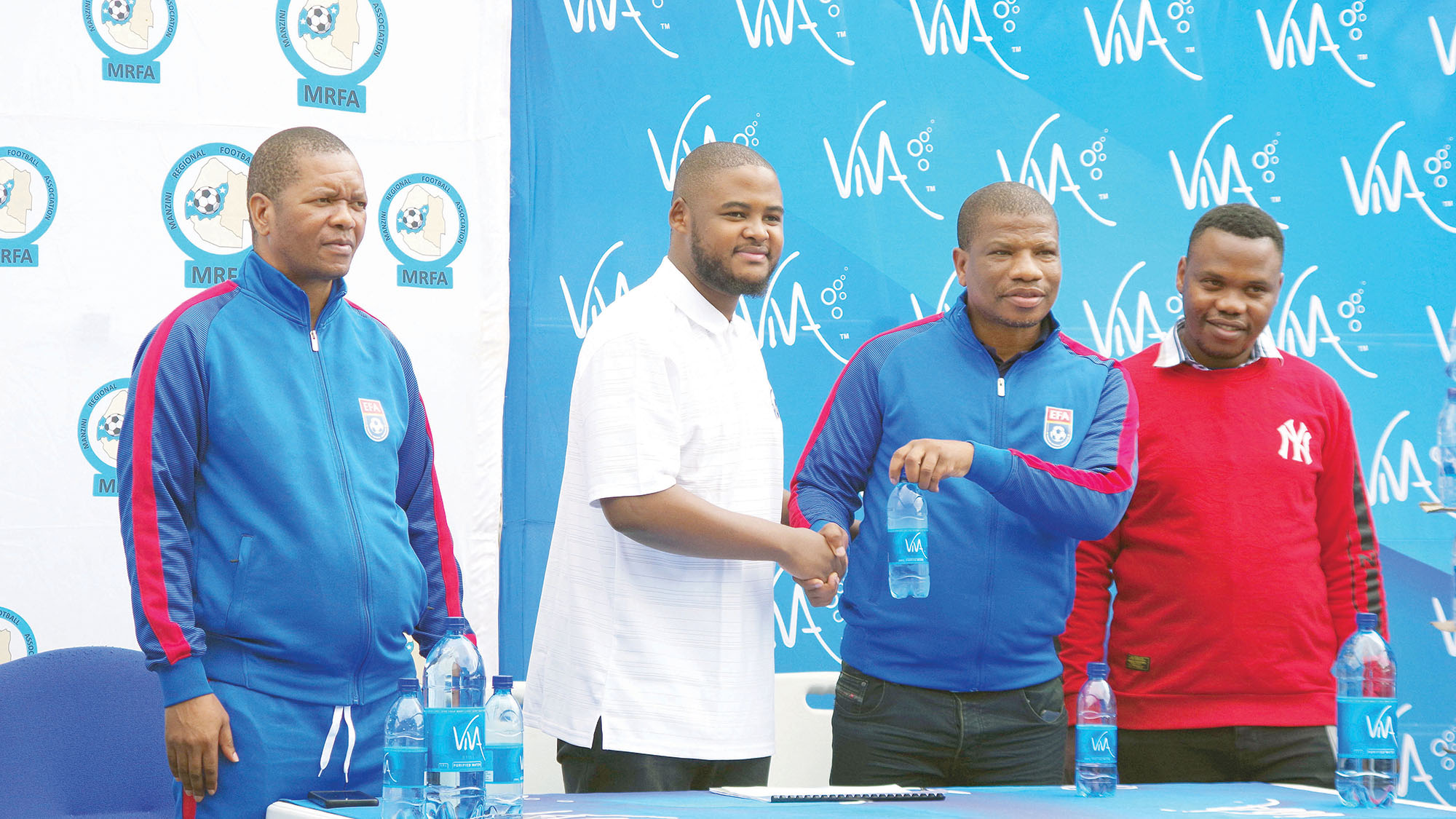 MRFA Chairman Vusie Hall receiving a bottle of VIVA Still Water from Operations Officer Yenzokuhle Nxumalo, while MRFA Executive Board member Mduduzi Tsabedze (L) and Acting Chief Operations Officer (COO) Muzi Mtsetfwa (R) follow proceedings during the partnership launch. (Pic: Ntombikayise Gwebu)